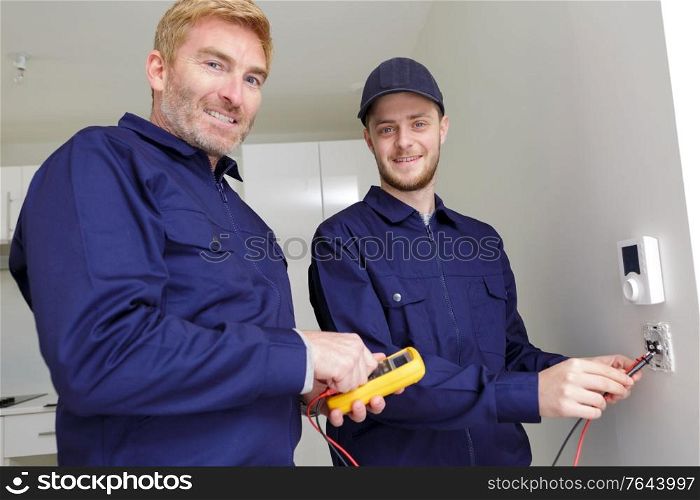 male workers measuring voltage in electrical wall