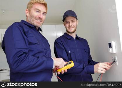 male workers measuring voltage in electrical wall