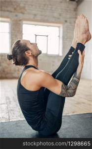 Male yoga in class, press training. Exercise on mat in gym with grunge interior. Fit workout indoors. Male yoga in class, press training