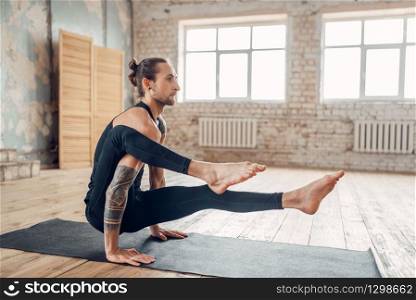 Male yoga in gym, balance exercise on mat. Fitness workout indoors. Healthy lifestyle. Male yoga in gym, balance exercise on mat