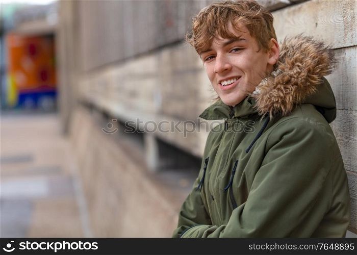Male young adult teenager wearing a parka jacket outside and smiling