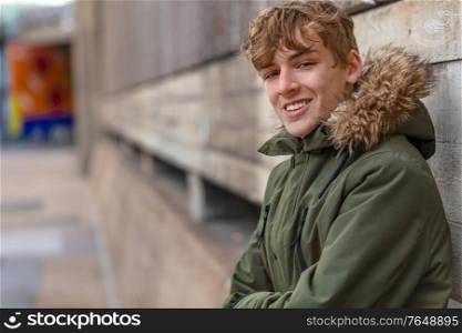 Male young adult teenager wearing a parka jacket outside and smiling