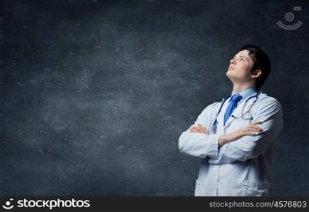 Male young doctor. Young man doctor on concrete background looking up