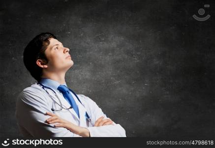 Male young doctor. Young man doctor on concrete background looking up