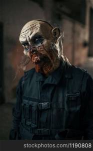 Male zombie walking in abandoned factory, scary place. Horror in city, creepy crawlies attack, doomsday apocalypse, bloody evil monster. Male zombie walking in abandoned factory