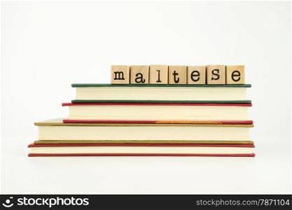 maltese word on wood stamps stack on books, foreign language and translation concept