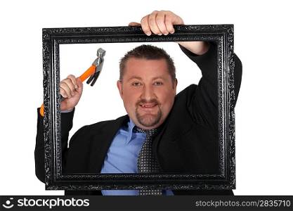 Man about to nail a picture frame to a wall