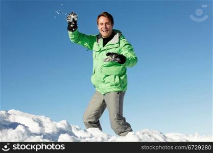 Man About To Throw Snowball Wearing Warm Clothes On Ski Holiday In Mountains