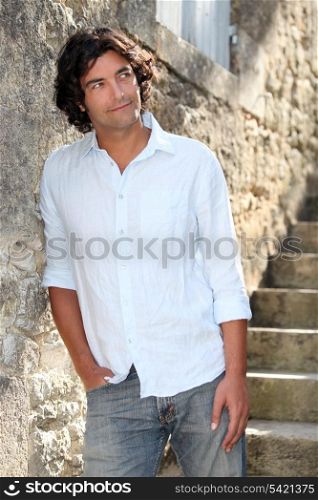 Man abroad leaning against old stone wall