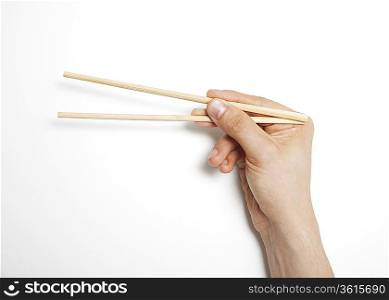 Man&acute;s hand gripping chopsticks over white background