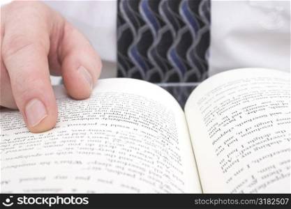 Man&acute;s Hand On Open Book: Close up of man pointing to page in open book.