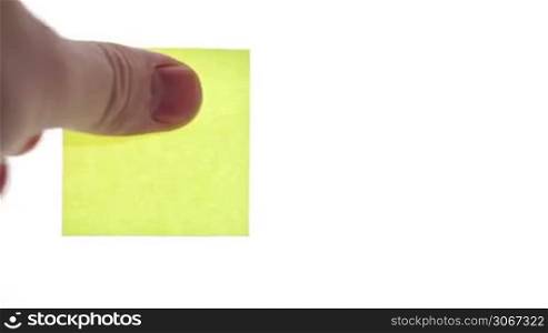 Man&acute;s hand put blank yellow sticker isolated on a white background. Ready for your inscription.