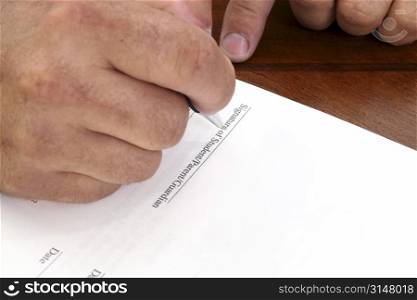 Man&acute;s hand signing contract. Line reads &acute;Signature of Student/Parent/Guardian&acute;.