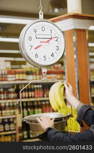 Man&acute;s hand weighing a bunch of bananas on a weighing scale in a supermarket