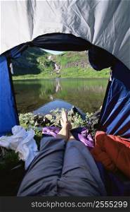 Man&acute;s legs in a tent overlooking scenic location