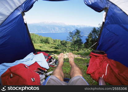 Man&acute;s legs in a tent overlooking scenic location