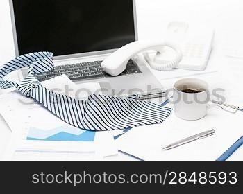 Man&acute;s tie laying on business office desk over laptop charts