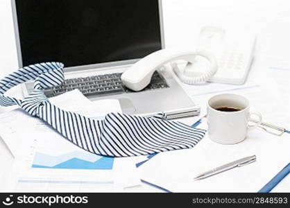 Man&acute;s tie laying on business office desk over laptop charts