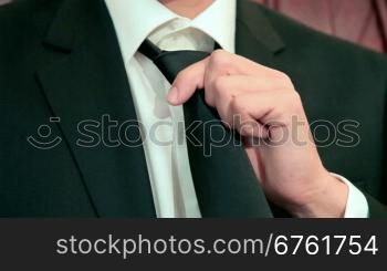man adjusting black tie