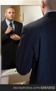 Man adjusting his tie in mirror