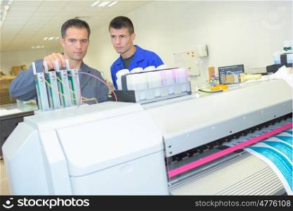 Man adjusting ink cartridges on professional printing machine