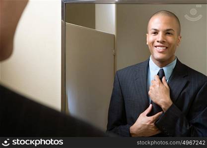 Man adjusting tie in mirror