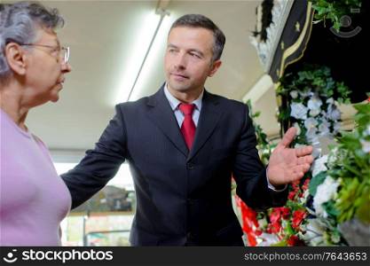 Man advising lady on funeral flowers