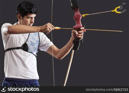 Man aiming bow and arrow isolated over black background