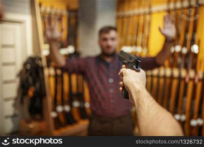 Man aims with new handgun on seller in gun shop. Male person buying pistol for security in weapon store, selfdefence and sport shooting hobby. Man aims with new handgun on seller in gun shop