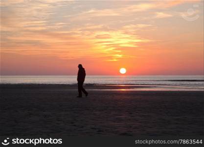 man alone on beach at sundown on the North Sea cost of the netherlands