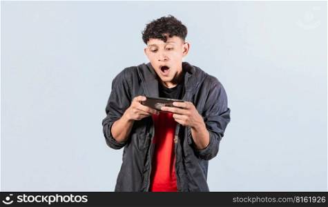 Man amazed holding cell phone horizontally, Guy gasping and playing games on his smartphone