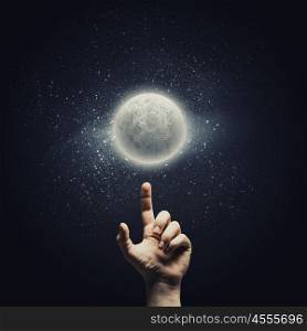 Man&amp;#39;s hand pointing at moon with finger