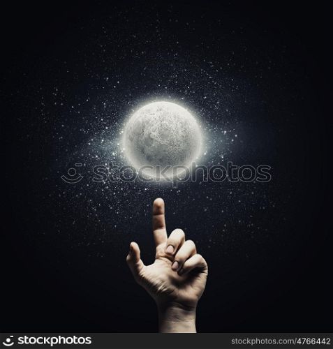 Man&amp;#39;s hand pointing at moon with finger