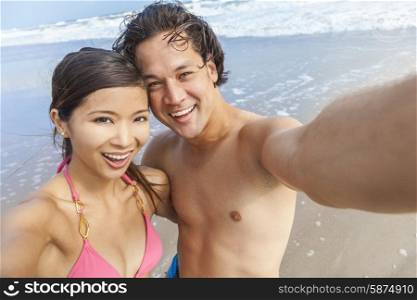 Man &amp; woman Asian couple, boyfriend girlfriend in bikini, taking vacation selfie photograph at the beach