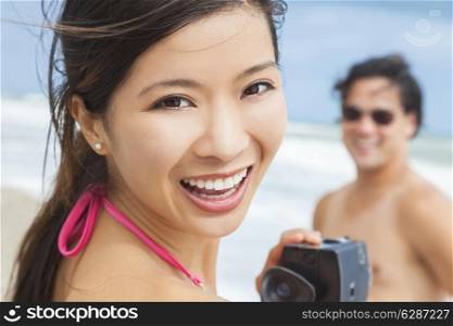 Man &amp; woman Asian couple, boyfriend girlfriend in bikini, taking vacation video or photograph at the beach