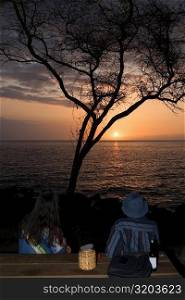 Man and a woman looking at sunset over the sea, Pakini Nui Wind Project, South Point, Big Island, Hawaii Islands, USA