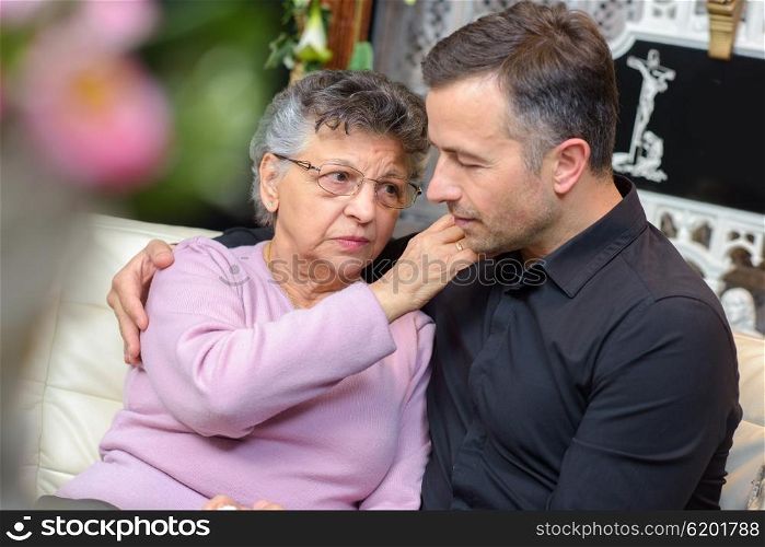 Man and elderly lady comforting each other