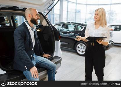 Man and female seller choosing auto in car dealership. Customer and saleswoman in vehicle showroom, male person buying transport, automobile dealer business. Man and female seller in car dealership