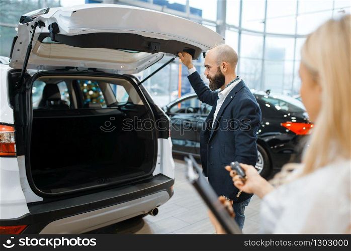 Man and female seller looking auto in car dealership. Customer and saleswoman in vehicle showroom, male person buying transport, automobile dealer business. Man and female seller looking auto, car dealership