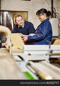 Man and female trainee preparing wood plank in printing workshop