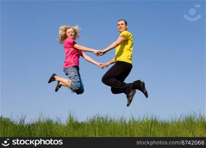 man and girl jumping on the green meadow