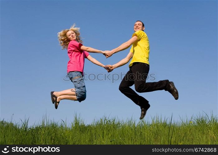 man and girl jumping on the green meadow