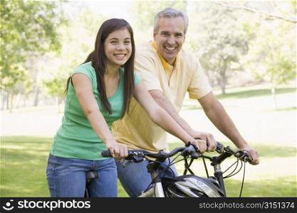 Man and girl on bikes outdoors smiling