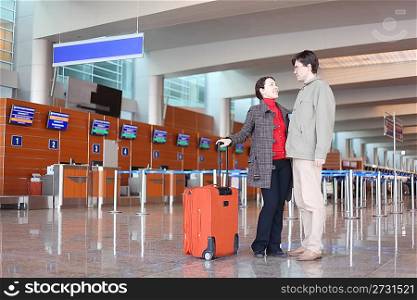 man and girl with red suitcase standing in airport hall