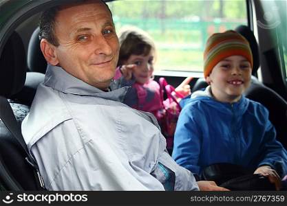 man and kids sit in the car