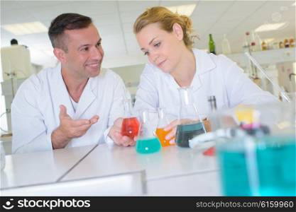 Man and lady in laboratory with glass flasks