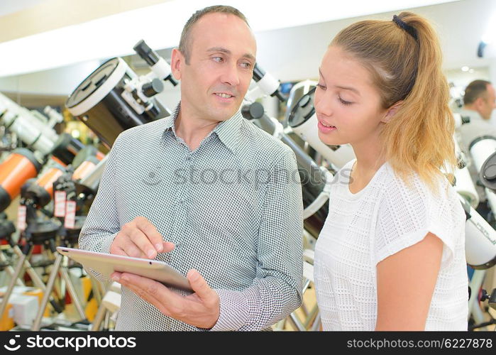 Man and lady looking at tablet in telescope store