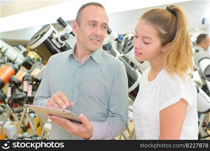 Man and lady looking at tablet in telescope store
