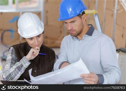 Man and lady on worksite looking at plans