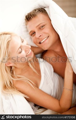 Man and lady smiling at camera and having fun in bed